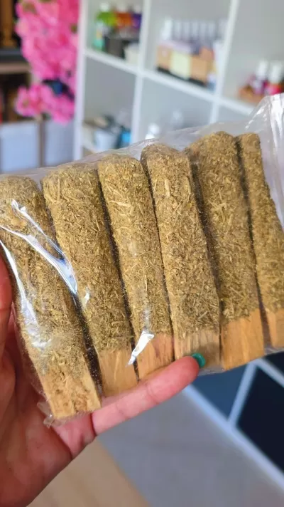 Pacote com sticks de madeira cobertos por ervas secas seguidos numa mão