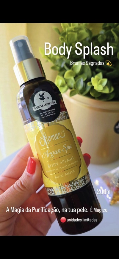 Frasco de body splash Ottoman Argan Spa com tampa prata e rótulo amarelo, 200 ml, visto de perto junto a planta verde.