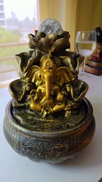 Fonte decorativa de Ganesha dourado com esfera transparente em base castanha