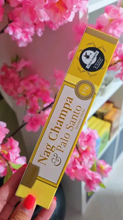 Embalagem amarela de incenso Nag Champa & Palo Santo com flores cor-de-rosa ao fundo