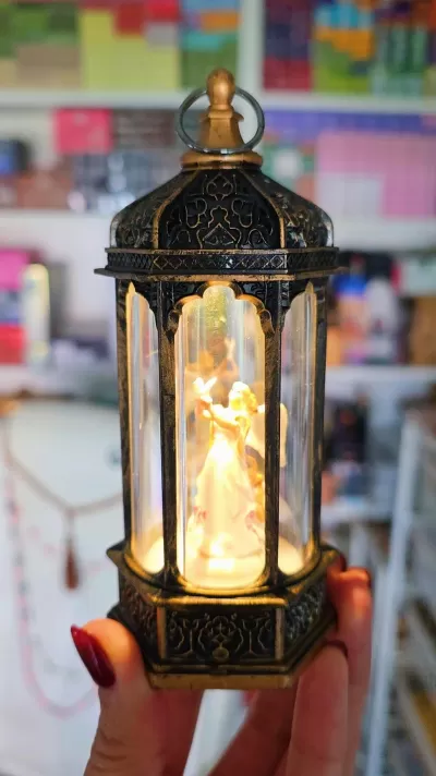 Lanterna decorativa de metal com vidro e anjo iluminado dentro