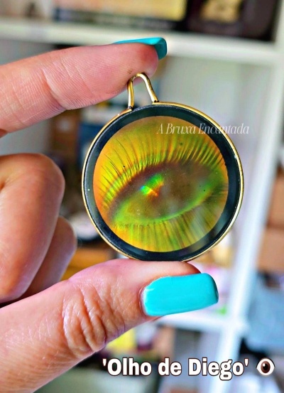 Colar com pendente redondo holográfico em forma de olho com moldura dourada.