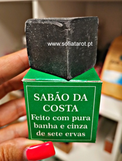 Sabonete preto em cubo sobre caixa verde com texto promotional em português.