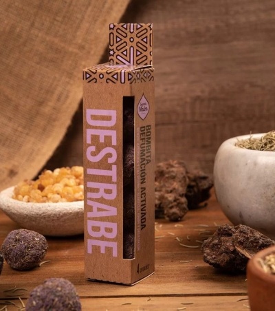 Caixa de papelão com texto DESTRABE e ingredientes naturais ao redor sobre fundo de madeira