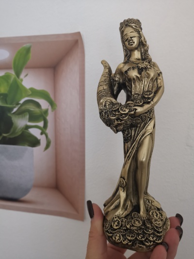 Estátua decorativa dourada de figura feminina vendada segurando cornucópia