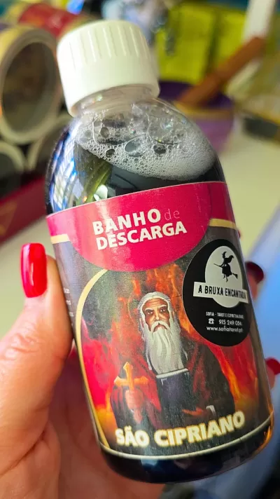 Frasco pequeno com líquido preto e rótulo vermelho e preto com texto e imagem de São Cipriano