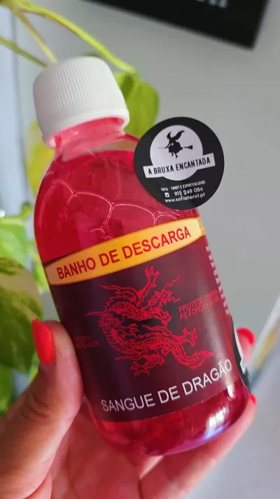Frasco com líquido vermelho e rótulo preto com dragão e texto em português.