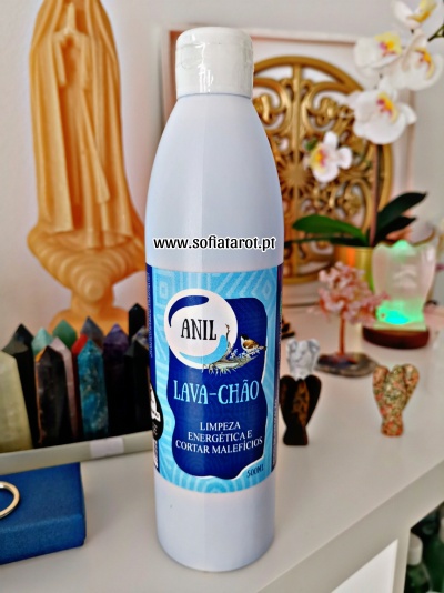 Frasco branco de lava-chão com rótulo azul e branco, sobre mesa com cristais e decoração