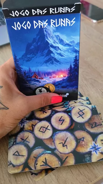 Caixa do jogo JOGO DAS RUNAS com ilustração de montanha nevada e cartas com runas sobre mesa