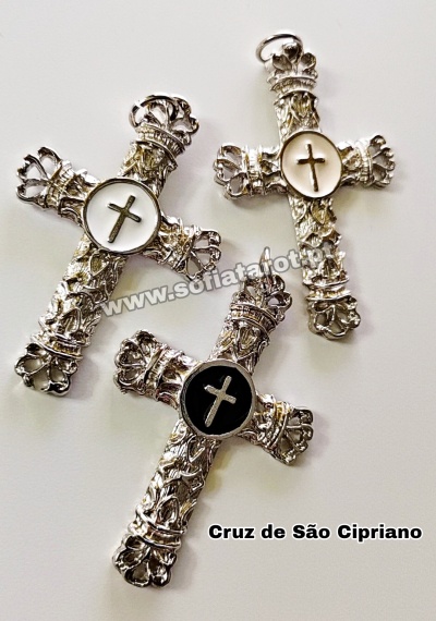 Três cruzes ornamentadas de metal prateado com círculos centrais contendo cruzes, duas brancas e uma preta.