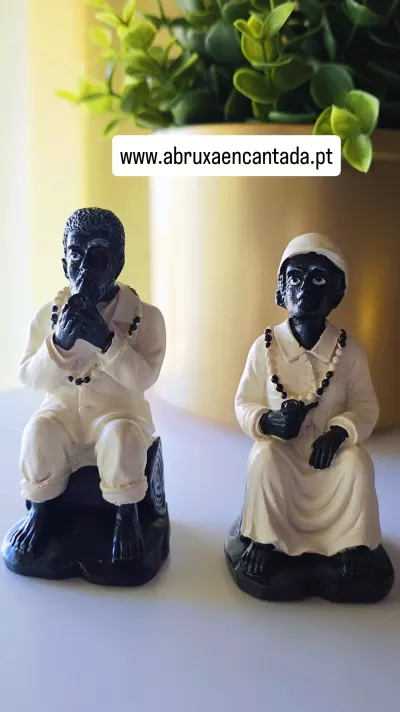 Estatuetas cerâmicas de figuras humanas sentadas, roupas brancas, colares de contas, base preta.
