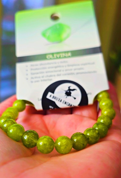 Pulseira de contas verdes com cartão informativo ao fundo