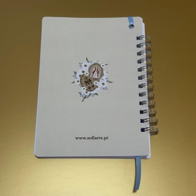 Caderno espiral branco com ilustração floral e fita azul sobre fundo dourado