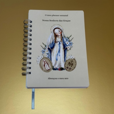 Planner semanal com capa creme e desenho de Nossa Senhora das Graças