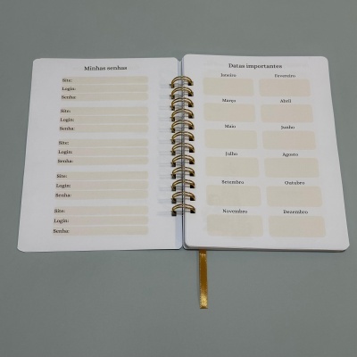 Caderno branco aberto mostrando páginas com campos para senhas e lista de meses do ano em português.