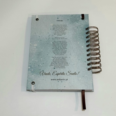 Caderno espiral azul claro com texto em português e padrão de manchas brancas