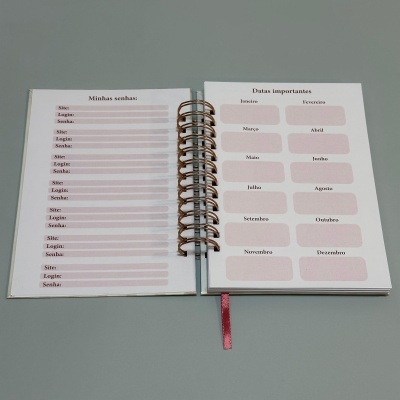 Caderno aberto com listas para senhas e datas importantes em páginas com espiral dourada