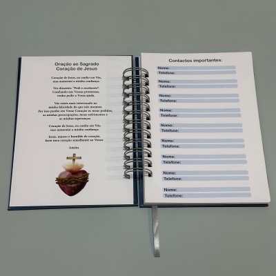 Livro de orações aberto mostrando uma oração e páginas para contactos com texto em português