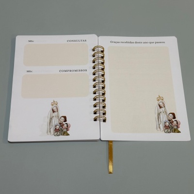 Agenda aberta com ilustrações religiosas e espaços para consultas, compromissos e orações em português.