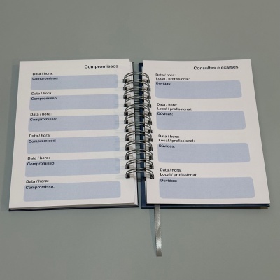 Agenda espiralada aberta com secções para compromissos e exames