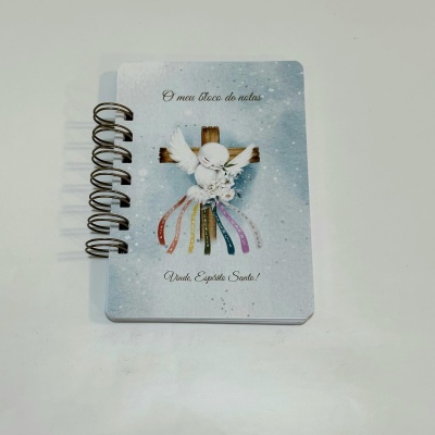 Bloco de notas com capa ilustrada com pomba branca e cruz, texto em português