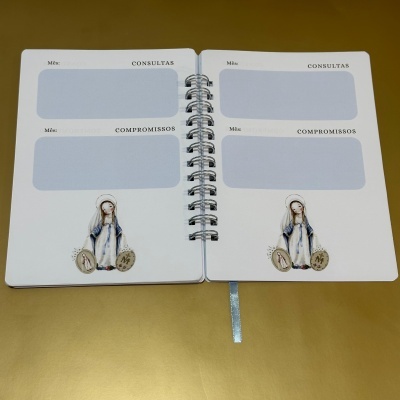 Agenda semanal aberta com espaços para consultas e compromissos e figura religiosa na página.