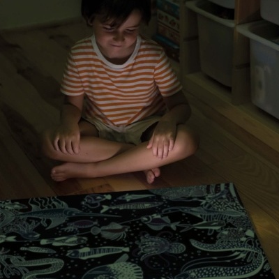 Criança sentada a olhar para tapete com padrões marinhos