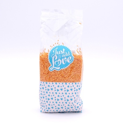 Pacote de confeitos de açúcar laranja com etiqueta Just add Love e padrão de corações azuis.