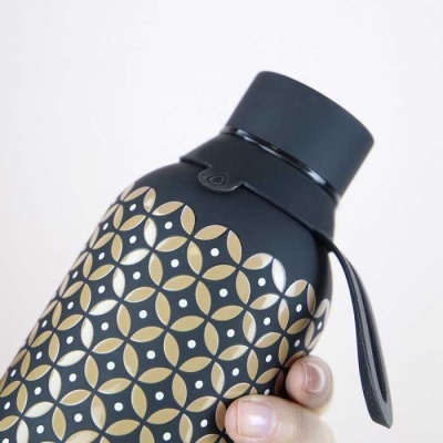 Garrafa térmica preta com padrão geométrico dourado e branco e pega lateral