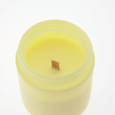 Vela amarela em frasco de vidro fosco com pavio de madeira