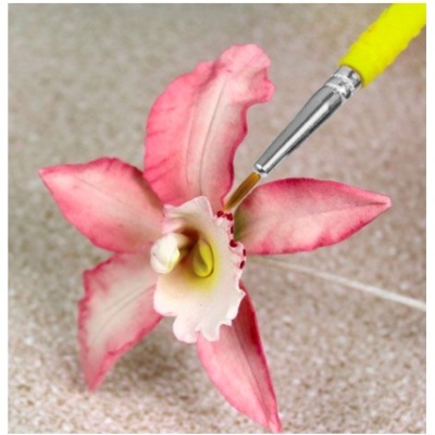 Pincel aplicando tinta vermelha em flor artificial rosa e branca