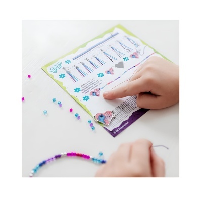 Criança a fazer pulseiras com contas coloridas seguindo instruções