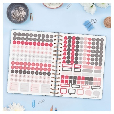 Caderno aberto com autocolantes coloridos e materiais de escritório sobre superfície azul