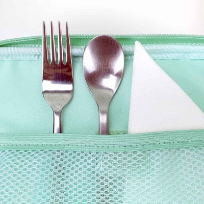 Garfo, colher e guardanapo dentro de bolso de tecido verde menta com fecho
