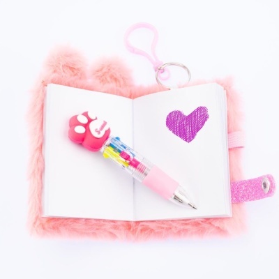 Caderno rosa peludo aberto com coração desenhado e caneta com topo em forma de pata
