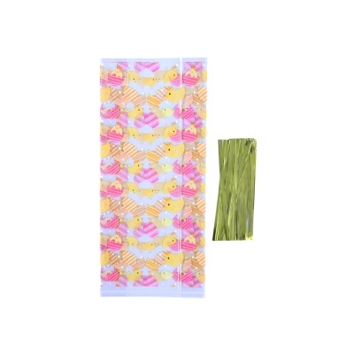 Saco plástico decorado com cupcakes coloridos e tiras metálicas douradas ao lado.