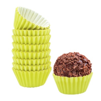 Formas de papel amarelas para doces empilhadas com um doce coberto de chocolate numa das formas.