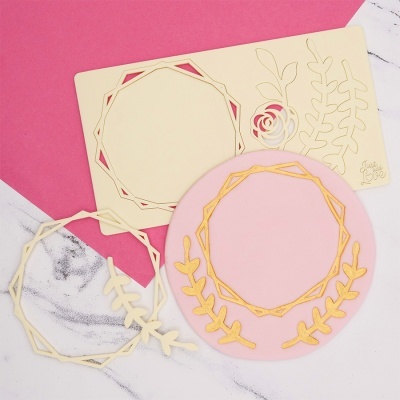 Stencil de plástico com recortes geométricos e florais e círculo rosa decorado com elementos dourados