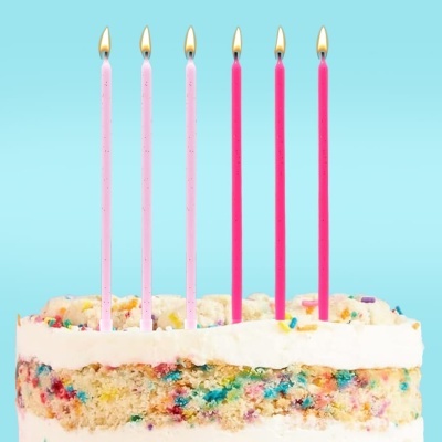 Bolo de aniversário com velas rosas finas acesas e cobertura branca com granulado colorido