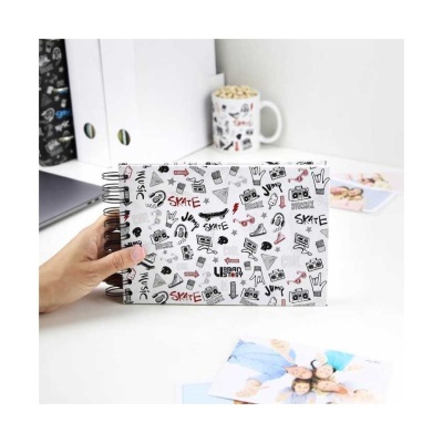 Caderno com capa branca decorada com desenhos e palavras em preto e vermelho sobre mesa branca