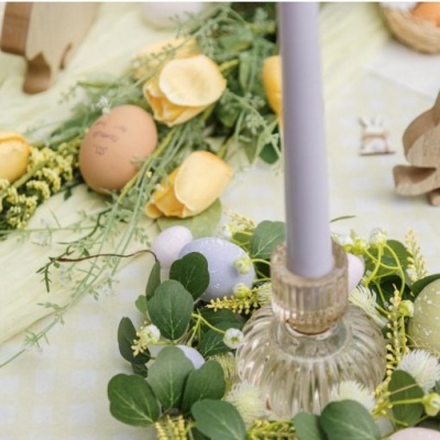 Arranjo decorativo com velas lilases, ovos coloridos e flores artificiais em tecido xadrez verde claro