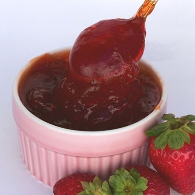 Taça rosa com geleia vermelha e morangos frescos