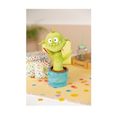 Boneco de peluche verde em vaso azul sobre mesa amarelo com confetes coloridos