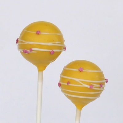 Dois cake pops amarelos decorados com fios brancos e flores cor-de-rosa.