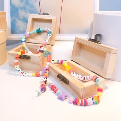 Caixas de madeira contendo pulseiras coloridas de miçangas com letras