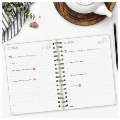 Agenda semanal aberta com anotações e bule branco ao lado