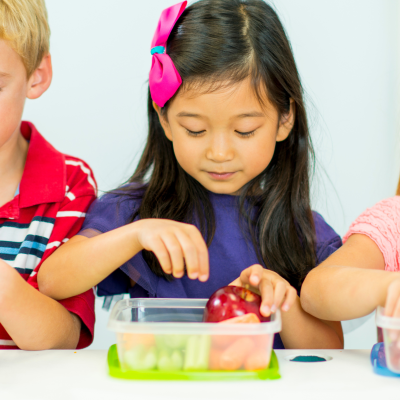 Três crianças a abrir caixas de frutas em ambiente interior