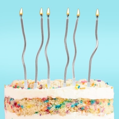 Bolo colorido com velas acesas num fundo azul