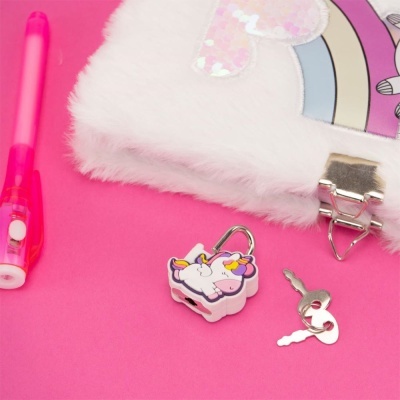 Caderno com capa felpuda branca, cadeado de unicórnio colorido, chaves prateadas e caneta rosa sobre fundo rosa