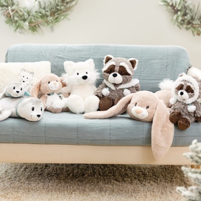 Sofá azul claro com vários peluches de animais e almofada branca